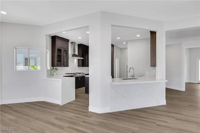2589 Sun Reef Rd, Las Vegas, NV 89128 - kitchen featuring wall chimney exhaust hood, light countertops, light wood-type flooring, a peninsula, and recessed lighting