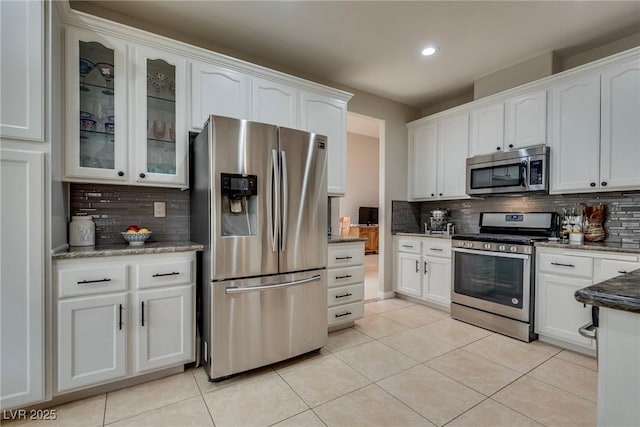kitchen featuring glass insert cabinets, decorative backsplash, stainless steel appliances, and white cabinetry