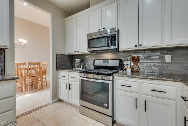 kitchen featuring stainless steel appliances, dark stone countertops, light tile patterned flooring, and decorative backsplash