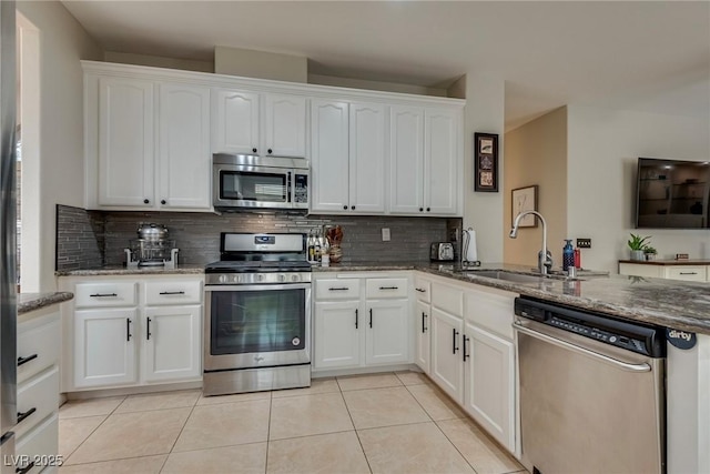 kitchen featuring a sink, stainless steel appliances, tasteful backsplash, light tile patterned floors, and white cabinets