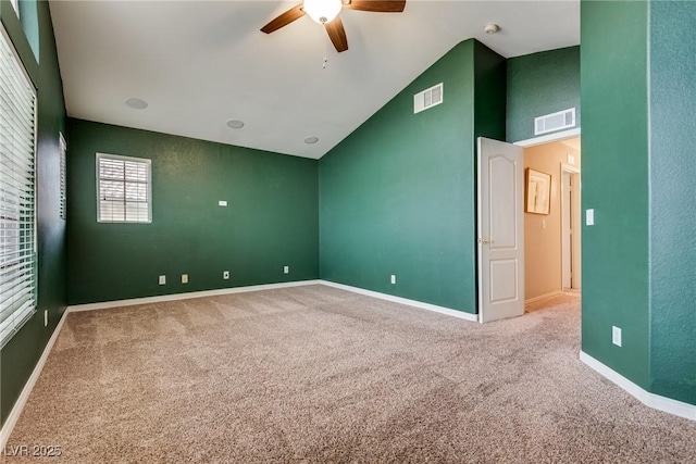 carpeted empty room featuring visible vents, baseboards, lofted ceiling, and ceiling fan
