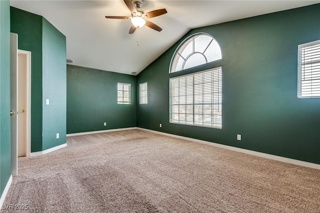 spare room with vaulted ceiling, carpet floors, a ceiling fan, and baseboards