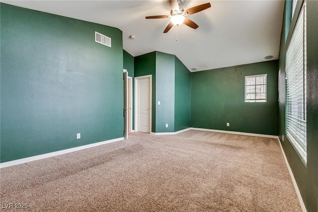 spare room with carpet flooring, visible vents, a ceiling fan, and vaulted ceiling