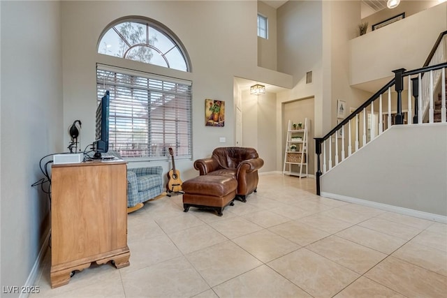 sitting room featuring stairs, light tile patterned flooring, a towering ceiling, and baseboards