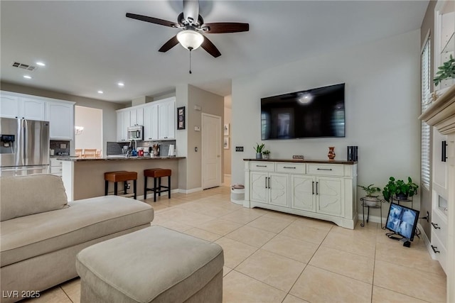 living room with light tile patterned floors, ceiling fan, baseboards, and visible vents