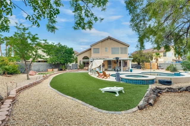 rear view of house with a pool with connected hot tub, a patio, stucco siding, a fenced backyard, and a lawn