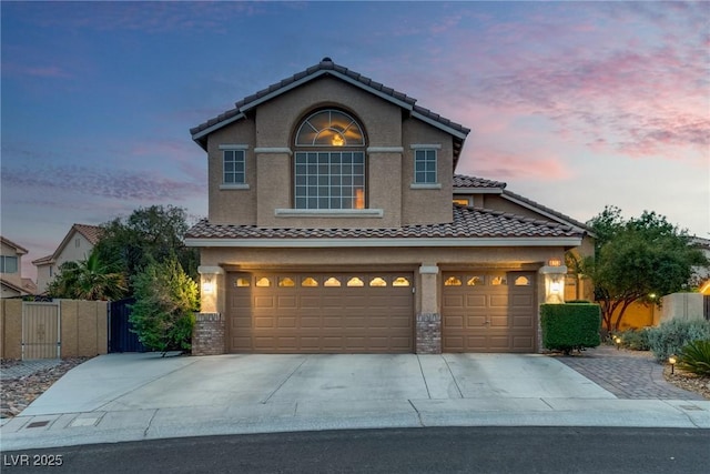 traditional-style house featuring stucco siding, concrete driveway, a garage, and a tiled roof