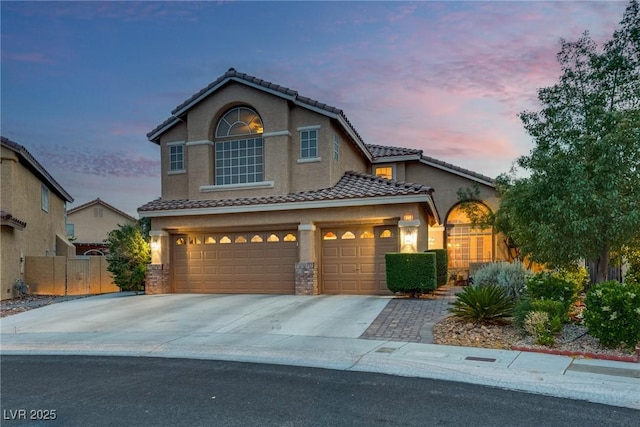 view of front facade featuring a garage, stucco siding, a tile roof, fence, and driveway