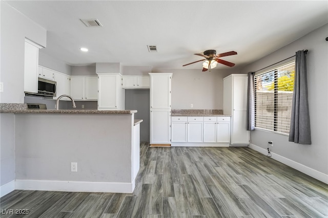 2046 Waverly Cir, Henderson, NV 89014 - kitchen featuring baseboards, stainless steel microwave, white cabinets, ceiling fan, and light wood-type flooring