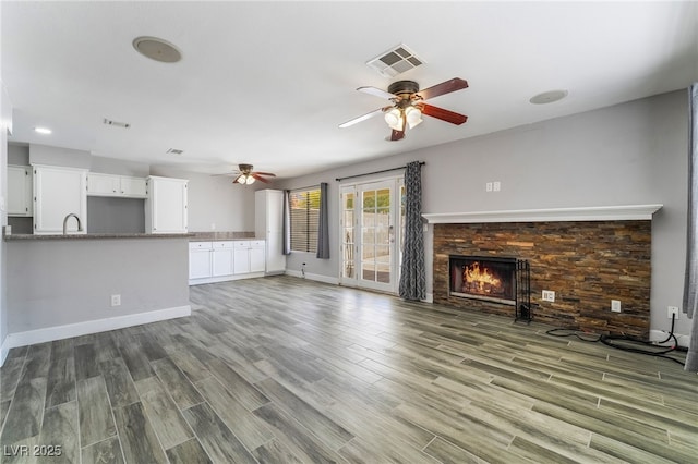 2046 Waverly Cir, Henderson, NV 89014 - unfurnished living room with ceiling fan, wood finished floors, a warm lit fireplace, baseboards, and a sink