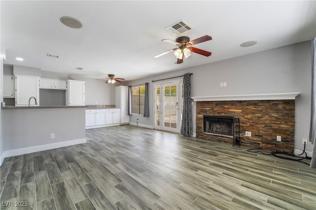 2046 Waverly Cir, Henderson, NV 89014 - unfurnished living room featuring ceiling fan, wood finished floors, a tile fireplace, baseboards, and a sink