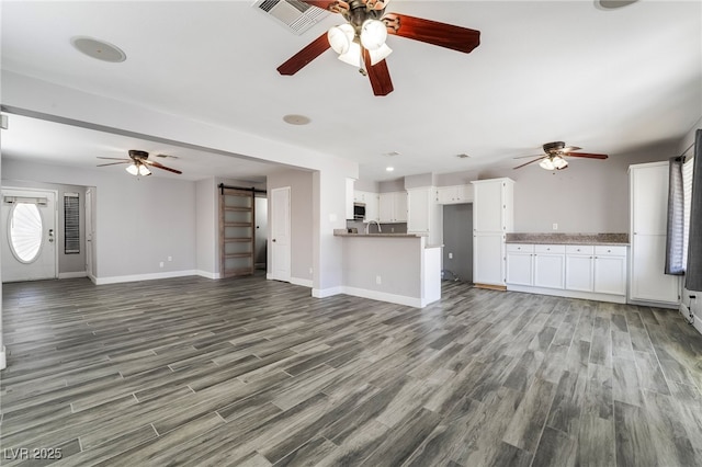 2046 Waverly Cir, Henderson, NV 89014 - unfurnished living room featuring a ceiling fan, a barn door, wood finished floors, and baseboards