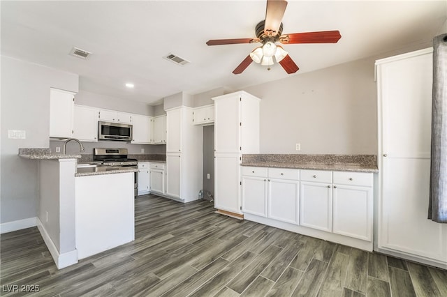 2046 Waverly Cir, Henderson, NV 89014 - kitchen with stainless steel appliances, a ceiling fan, dark wood-style flooring, baseboards, and white cabinets
