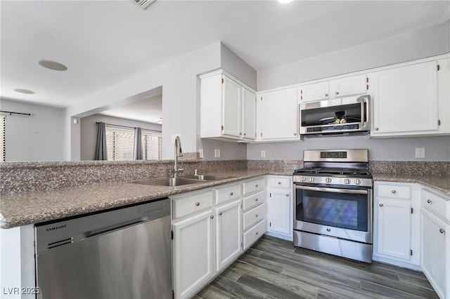 2046 Waverly Cir, Henderson, NV 89014 - kitchen with appliances with stainless steel finishes, a sink, white cabinetry, dark wood-style flooring, and a peninsula