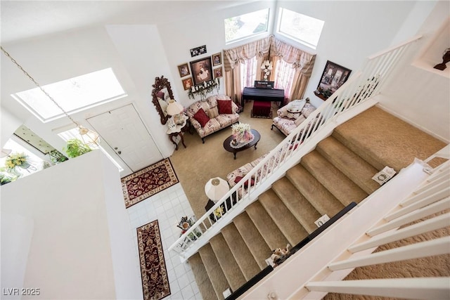 stairs featuring carpet floors, a skylight, and a towering ceiling