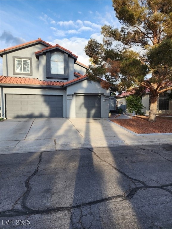 mediterranean / spanish home with concrete driveway, stucco siding, a tile roof, and a garage