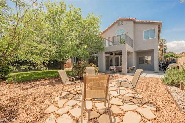 back of property with a patio, stucco siding, outdoor dining space, and a balcony