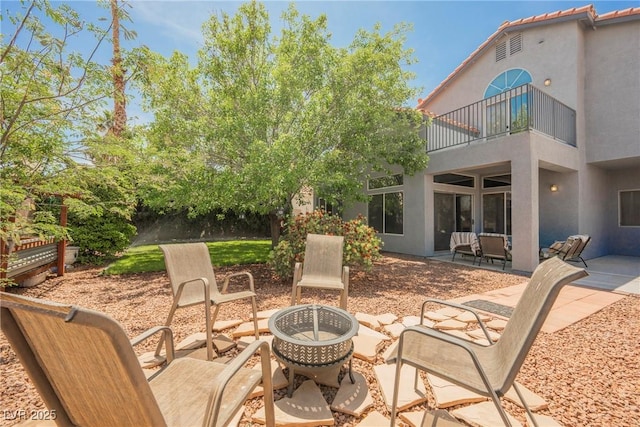 view of patio / terrace with an outdoor fire pit and a balcony