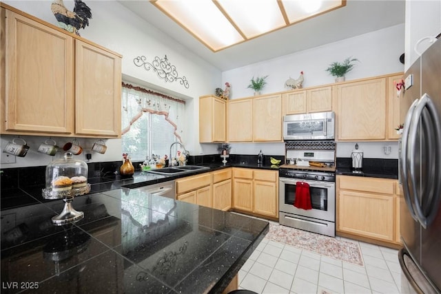 kitchen with light tile patterned floors, a sink, light brown cabinetry, stainless steel appliances, and tile countertops