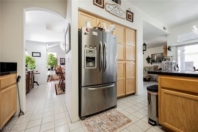 kitchen with a wealth of natural light, arched walkways, stainless steel refrigerator with ice dispenser, and light tile patterned floors
