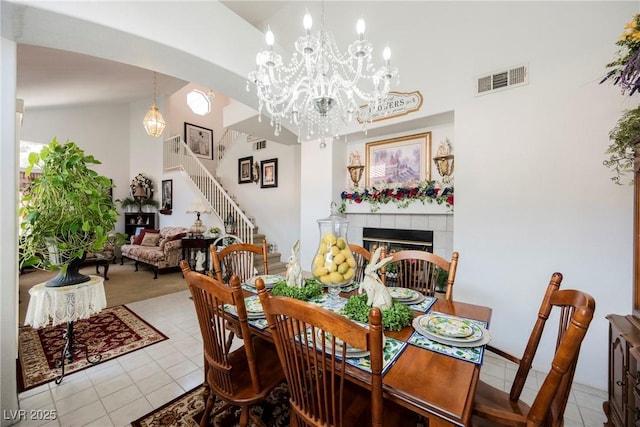 dining area with lofted ceiling, stairs, visible vents, a fireplace, and light tile patterned floors