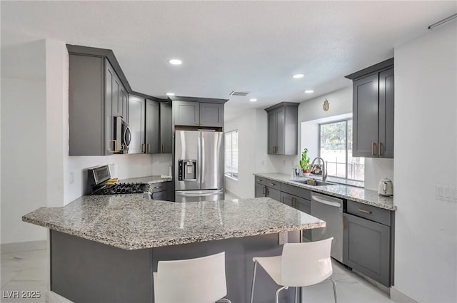 8404 Shore Breeze Dr, Las Vegas, NV 89128 - kitchen with appliances with stainless steel finishes, a peninsula, a sink, light marble finish flooring, and light stone counters