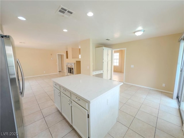 7840 Millhopper Ave, Las Vegas, NV 89128 - kitchen with freestanding refrigerator, light tile patterned flooring, white cabinetry, a center island, and open floor plan