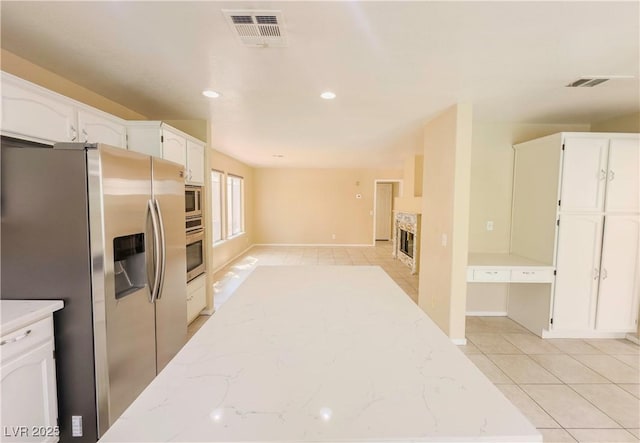 7840 Millhopper Ave, Las Vegas, NV 89128 - kitchen featuring appliances with stainless steel finishes, white cabinetry, light stone counters, light tile patterned floors, and baseboards