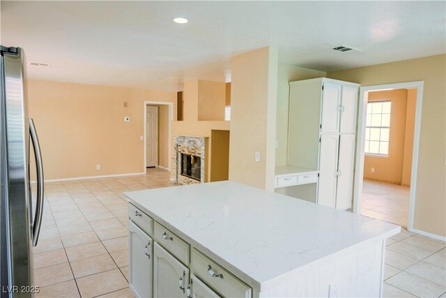 7840 Millhopper Ave, Las Vegas, NV 89128 - kitchen with freestanding refrigerator, light tile patterned flooring, a kitchen island, baseboards, and a tiled fireplace