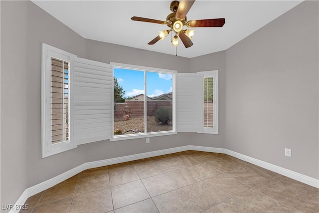 tiled spare room featuring baseboards and ceiling fan