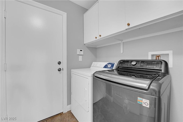 clothes washing area with washing machine and clothes dryer, baseboards, and cabinet space