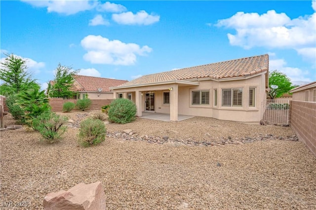 rear view of house featuring stucco siding, a tile roof, a fenced backyard, and a patio area