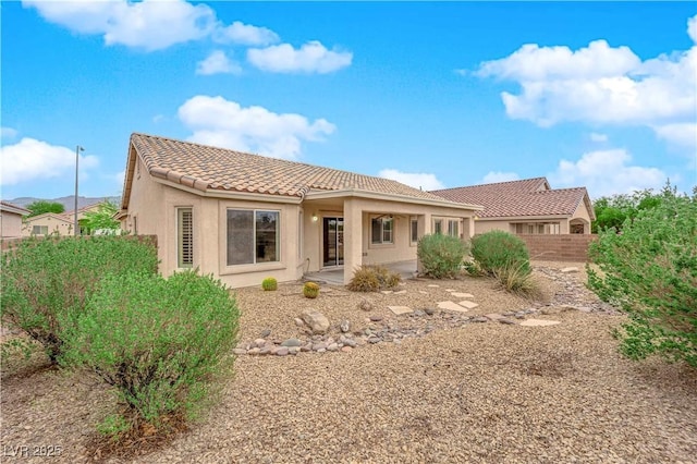 back of house with a tile roof, fence, a patio, and stucco siding