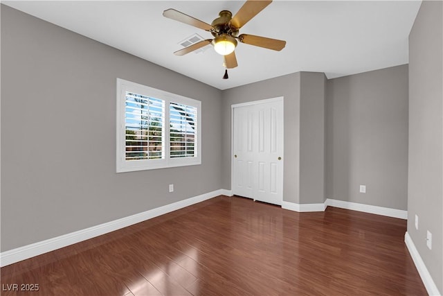 unfurnished bedroom with baseboards, dark wood-type flooring, visible vents, and a closet