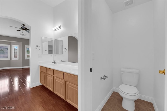 bathroom featuring toilet, wood finished floors, visible vents, baseboards, and ceiling fan