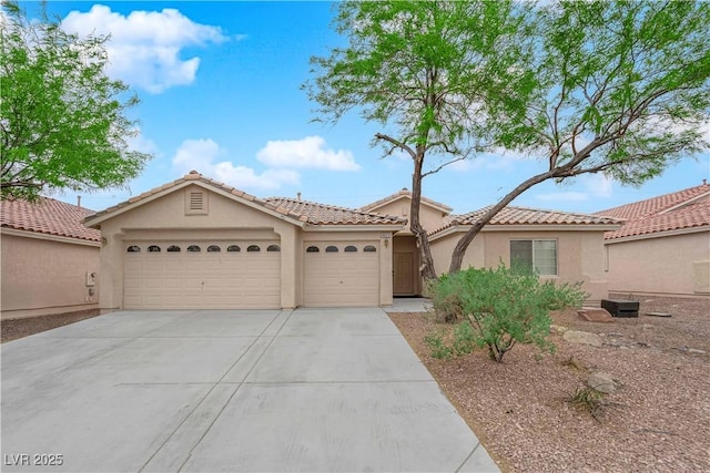 view of front of property with driveway, stucco siding, a tiled roof, and an attached garage