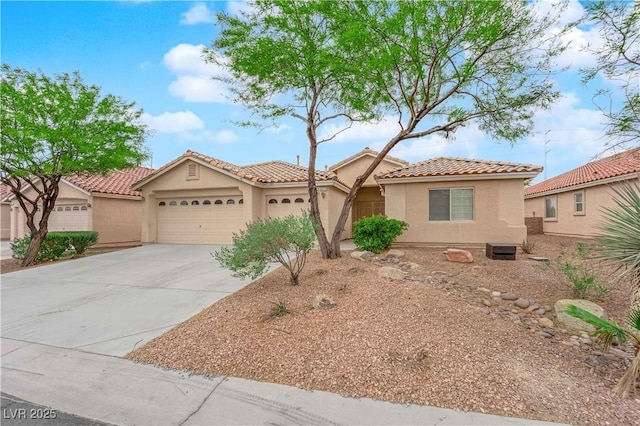 mediterranean / spanish house with concrete driveway, stucco siding, a tile roof, and a garage