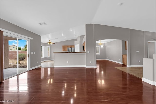 unfurnished living room with arched walkways, visible vents, a ceiling fan, and vaulted ceiling