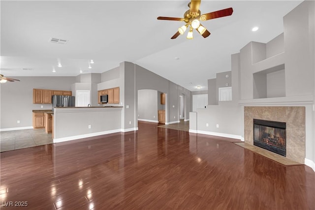 unfurnished living room featuring a high end fireplace, wood finished floors, visible vents, a ceiling fan, and baseboards