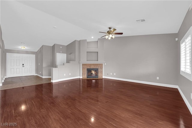 unfurnished living room featuring wood finished floors, visible vents, vaulted ceiling, a ceiling fan, and baseboards