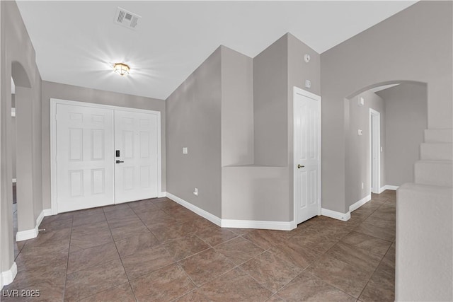 entrance foyer with arched walkways, baseboards, and visible vents