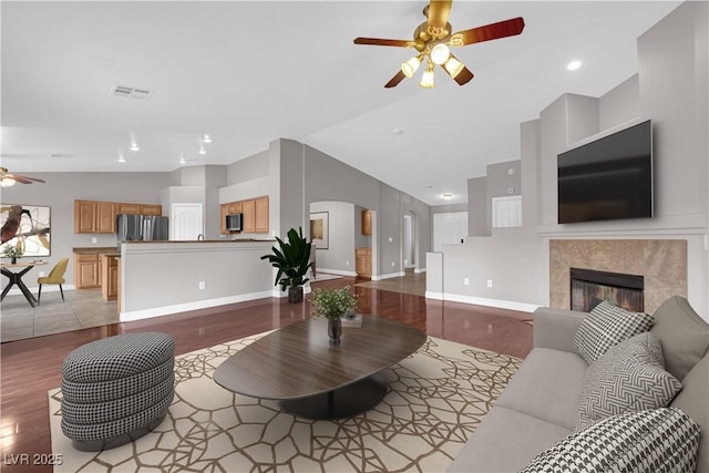 living room with lofted ceiling, wood finished floors, visible vents, ceiling fan, and baseboards