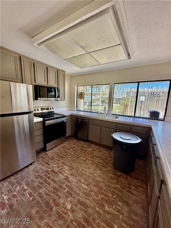 4662 Kelly Barry Way, Las Vegas, NV 89121 - kitchen with appliances with stainless steel finishes, light countertops, brick flooring, and a textured ceiling