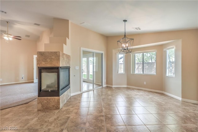8664 Frasure Falls Ave, Las Vegas, NV 89178 - unfurnished living room featuring a tiled fireplace, baseboards, visible vents, and ceiling fan with notable chandelier
