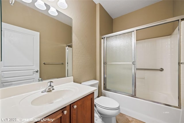 bathroom featuring toilet, tile patterned flooring, vanity, and shower / bath combination with glass door