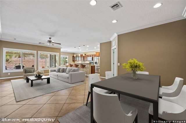 dining space with a ceiling fan, visible vents, light tile patterned flooring, and ornamental molding
