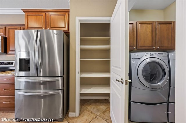 laundry area featuring cabinet space, washing machine and clothes dryer, and light tile patterned floors