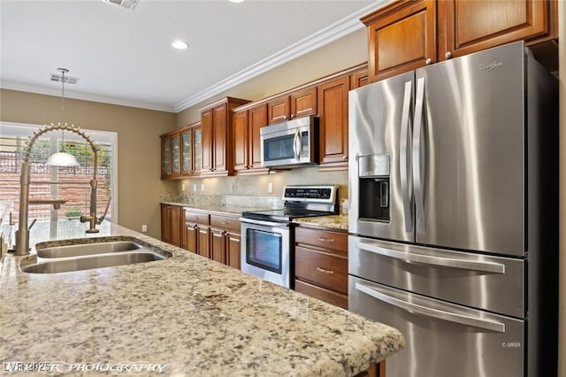 kitchen with a sink, ornamental molding, brown cabinets, and appliances with stainless steel finishes