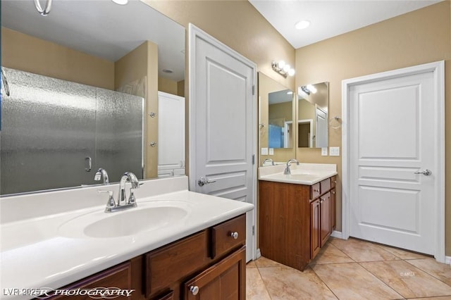 full bath with tile patterned flooring, a shower with door, two vanities, and a sink