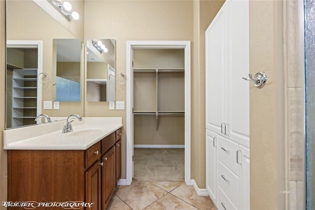 bathroom with baseboards, a spacious closet, tile patterned floors, and vanity